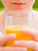 Extreme close up of young woman holding a glass of orange juice\n