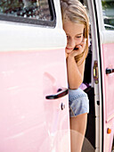 Porträt eines jungen Mädchens, das in einem rosa Lieferwagen sitzt