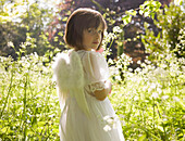 Portrait eines jungen Mädchens im weißen Feenkostüm im Garten stehend
