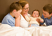 Portrait einer Frau im Bett mit ihren Kindern und ihrem Neugeborenen