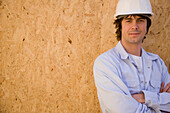 Portrait eines jungen Mannes mit Schutzhelm auf einer Baustelle