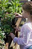 Junges Mädchen in einer Gärtnerei beim Betrachten von Pflanzen