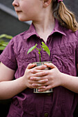Close up of young girl holding a plant\n