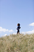 Young woman running through sand dunes\n