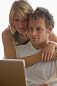 Young couple looking at laptop computer screen embracing\n