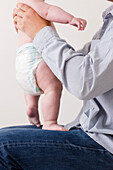 Man sitting with newborn baby standing on his lap\n