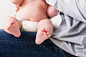 Man legs with newborn baby on his lap\n