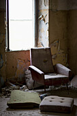 Dusty armchair in dirty and empty room\n