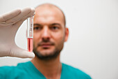 Healthcare professional holding a test tube between his fingers\n