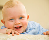 Close up of cute baby boy with face resting on hands\n