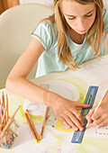 Junges Mädchen zeichnet mit einem Lineal für Linkshänder