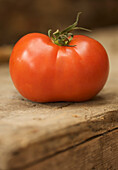 Close up of a red vine tomato on a wooden surface\n