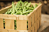 Close up of a wooden crate filled with broad beans\n