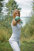 Junge Frau streckt sich und balanciert eine Kugel in einer Hand