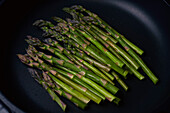 Vibrant green asparagus cooking in pan\n