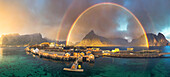 Aerial view of idyllic rainbows over Olstind mountain and fishermen cabins by the sea, Sakrisoy, Reine, Lofoten Islands, Nordland, Norway, Scandinavia, Europe\n