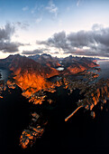 Panoramablick aus der Luft auf das Küstendorf Tind eingerahmt von Bergen bei Sonnenuntergang, Lofoten Inseln, Nordland, Norwegen, Skandinavien, Europa