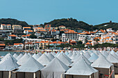 View of green huts at Sao Martinho do Porto beach, a wide white-sand beach, backed by dunes in a secluded bay popular with families, Oeste, Portugal, Europe\n