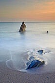 Surf rolls around shoreline rocks at sunset, in Ayrmer Cove, a remote cove near Kingsbridge, south coast of Devon, England, United Kingdom, Europe\n