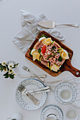 Schwedischer Sandwichkuchen mit Krabben, Käse, Schinken und Eiern auf Holzbrett am Tisch