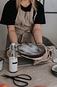 Frau stellt frisch gebackenen Schokoladenkuchen auf den Tisch