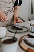 Frau legt ein Stück frisch gebackenen Schokoladenkuchen auf einen Teller