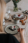 Woman eating chocolate cake with cream and raspberries\n