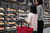 Pärchen mit Einkaufskorb in der Bäckereiabteilung eines Supermarktes