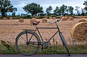 Bicycle in front of summer field with bales of straw\n