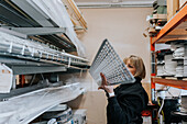 Female worker taking equipment from shelf\n