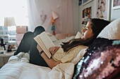 Girl relaxing in bedroom and reading book\n