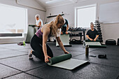 People rolling up mats after workout at gym\n