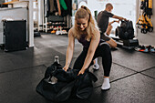 Frau packt Ausrüstung nach dem Training im Fitnessstudio