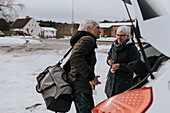 Senior women packing bags in car after workout in gym\n