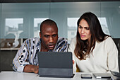 Mitarbeiter sitzen bei einem Geschäftstreffen und schauen auf ein digitales Tablet