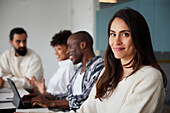 Smiling woman sitting during business meeting and looking at camera\n