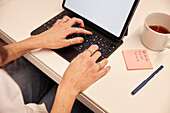 Blick von oben auf die Hände einer Frau bei der Benutzung eines Laptops