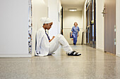 Female doctor sitting on hospital corridor floor\n