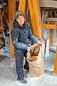 Smiling woman in mill holding sack with flour inside\n
