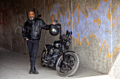Mature biker in leather clothes standing next to motorcycle\n