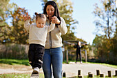 Mother helping daughter to keep balance at playground\n