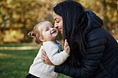 Happy mother hugging daughter in park\n