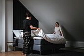 Women making bed together in morning\n