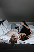 Homosexuelles Paar liegt im Bett und schaut sich an