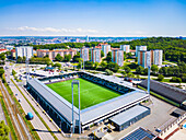 High angle view of football stadium and blocks of flats in background\n