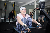 Smiling senior woman exercising in gym\n