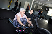 Coach assisting to senior woman exercising in gym\n