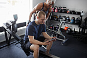 Mann und Frau schauen auf ein digitales Tablet in einem Fitnessstudio