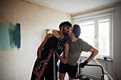 Male homosexual couple kissing while renovating their apartment\n