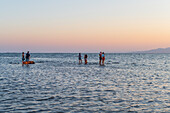 Menschen genießen den Sonnenuntergang am Strand von Trabucador, Ebro-Delta, Tarragona, Spanien